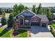 Attractive brick-fronted home with mature trees, manicured lawn and a three-car garage, creating a welcoming appeal at 7472 Iridium Way, Castle Rock, CO 80108