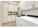 Efficient laundry room with white cabinetry, granite countertops, modern washer and dryer, and tiled floor at 9316 E Harvard Ave, Denver, CO 80231