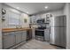 Modern kitchen with stainless steel appliances, gray cabinets, and bright natural light from the window at 6705 S Field St # 801, Littleton, CO 80128