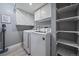 Functional laundry room with modern washer and dryer, upper cabinets, and shelving for storage at 6705 S Field St # 801, Littleton, CO 80128
