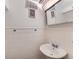 A clean, white tiled bathroom featuring a pedestal sink and a mirrored medicine cabinet at 2626 N Steele St, Denver, CO 80205