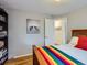 A cozy bedroom with a rainbow blanket, wooden bed frame, and a decorative black and white print at 2626 N Steele St, Denver, CO 80205