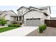 Charming two-story home with gray siding, stone accents, landscaped yard, and a welcoming covered porch at 14454 Grape Way, Brighton, CO 80602