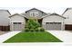 Inviting two-story home with manicured lawn, complemented by symmetrical landscaping and dual garage doors at 14454 Grape Way, Brighton, CO 80602