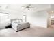 Bright main bedroom with tray ceilings, ceiling fan, neutral carpet and a view into the en-suite bathroom at 14454 Grape Way, Brighton, CO 80602
