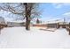 Snowy backyard featuring a mature tree, storage shed, wooden sandbox, and a cozy patio area at 11 S Perry St, Denver, CO 80219