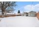 Large, snow-covered backyard with mature tree, storage shed, and patio area for outdoor entertaining at 11 S Perry St, Denver, CO 80219