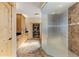 This bathroom features a glass shower, wooden cabinets, tile floor and is adjacent to the walk-in closet at 7398 Weaver Cir, Castle Rock, CO 80104