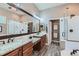 Luxurious bathroom featuring double sinks, granite countertops, glass-enclosed shower and wood look tile floors at 4285 Corte Bella Dr, Broomfield, CO 80023