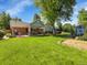 Beautiful backyard with a covered patio, swing, mature trees, lush green lawn, and attractive landscaping at 6810 S Marion W Cir, Centennial, CO 80122