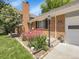 Charming entrance featuring brick accents, a well-maintained lawn, and beautiful landscaping with vibrant flowers at 6810 S Marion W Cir, Centennial, CO 80122