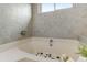 Bright bathroom featuring a soaking tub, neutral tile surround, and natural light from the window at 402 Roosevelt St, Palmer Lake, CO 80133