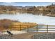 Tranquil view of a partially frozen pond with a wooden fence and a bench in the foreground at 402 Roosevelt St, Palmer Lake, CO 80133