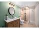 Bathroom with a wood vanity, round mirror, decorative light fixture, and tiled shower stall at 6173 Eldora St, Golden, CO 80403