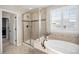 Bathroom showcasing a glass shower, soaking tub, tiled floors, and shuttered window at 6173 Eldora St, Golden, CO 80403