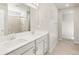 Bright bathroom with dual vanity sinks, white cabinetry, and a tiled shower, blending functionality with style at 8879 Sedalia St, Commerce City, CO 80022