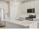 Contemporary kitchen with white cabinetry, stainless steel appliances, and a spacious quartz-topped island at 8879 Sedalia St, Commerce City, CO 80022