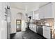 Modern kitchen features white cabinets, stainless appliances, black tile flooring, and a stylish arched doorway to the yard at 3250 N Clayton St, Denver, CO 80205