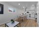 Open concept dining area featuring hardwood floors, pendant lighting, and modern white kitchen at 6641 Ash St, Commerce City, CO 80022