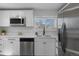 Bright kitchen features stainless appliances, white cabinets, quartz countertop, and sink under the window at 6641 Ash St, Commerce City, CO 80022
