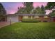 Charming single-story brick home with a well-manicured lawn and attached garage at dusk at 13558 E Center Ave, Aurora, CO 80012