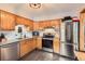 Well-lit kitchen with stainless steel appliances and natural wood cabinets at 13558 E Center Ave, Aurora, CO 80012