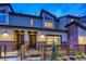Stylish townhome featuring modern design, a mix of brick and siding, and an inviting fenced front yard at twilight at 12339 W 58Th Ct, Arvada, CO 80004