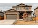 Charming two-story home boasts a large garage, covered front porch, and stylish brown color scheme at 15920 Hayloft Ln, Parker, CO 80134