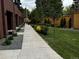 Townhome exterior with a sidewalk flanked by manicured landscaping and a wooden fence at 2142 Applewood Dr, Lakewood, CO 80215