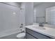 Bathroom featuring gray cabinets, a white countertop, and shower with white tile at 8585 Eckley St, Littleton, CO 80125
