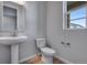 Powder room features a pedestal sink, toilet, and window for ample natural light at 8585 Eckley St, Littleton, CO 80125