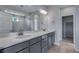 A bright bathroom featuring double sinks, gray cabinets, and a glass enclosed shower at 8585 Eckley St, Littleton, CO 80125