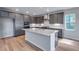 Modern kitchen with gray cabinets, stainless steel appliances, an island, and light hardwood floors at 8585 Eckley St, Littleton, CO 80125