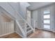 Open staircase features carpeted steps, white banisters and a light-filled foyer with wood-look floors at 8585 Eckley St, Littleton, CO 80125