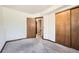 A carpeted bedroom with an open closet door and a closed closet and a view to stairs at 9125 W 95Th Ave, Westminster, CO 80021