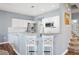 A bright kitchen with white cabinetry, granite countertops, stainless steel appliances, and a cozy breakfast bar at 7524 Pineridge Trl, Castle Pines, CO 80108