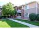 Well-maintained condo exterior featuring brick accents, neutral siding, and mature trees with lush landscaping at 8481 W Union Ave # 2-201, Littleton, CO 80123