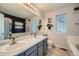 Well-lit bathroom featuring double sinks, a large mirror, bathtub and shower, and a separate toilet at 16442 Bluebonnet Dr, Parker, CO 80134