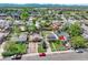 Aerial view of a neighborhood with a yellow house and surrounding homes and lush greenery at 6671 Grove St, Denver, CO 80221