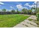 Large backyard with a mix of grass and concrete, surrounded by a wooden fence for privacy at 6671 Grove St, Denver, CO 80221