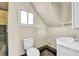 Cozy bathroom featuring a toilet, sink, window and neutral walls under an angled ceiling at 6671 Grove St, Denver, CO 80221