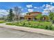 Charming two-story home with a fenced front yard, mature trees, and blue sky at 6671 Grove St, Denver, CO 80221