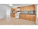 Bright kitchen featuring wood cabinets and white appliances with neutral tile flooring throughout at 6671 Grove St, Denver, CO 80221