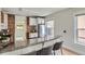Bright kitchen featuring white cabinets, stainless steel refrigerator, brick accent wall, granite counters and bar seating at 2562 N Emerson St, Denver, CO 80205