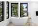 Soaking tub with gold fixtures, next to windows with neighborhood view at 1126 S Garfield St, Denver, CO 80210