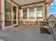 This covered patio features a table and chairs, wood decking and siding and three windows at 1297 Black Haw St, Elizabeth, CO 80107