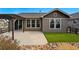 Rear view of the house with a patio, grassy area, rock garden, and well-maintained landscaping at 15851 Josephine Cir, Brighton, CO 80602