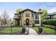 Stunning stone home with a manicured lawn, decorative planters, and a wrought iron fence in a lush green neighborhood at 2400 S Columbine St, Denver, CO 80210