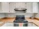 Bright kitchen featuring white cabinetry and an electric range with sleek stainless steel vent hood at 1068 Milo Cir # A, Lafayette, CO 80026