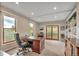 Home office featuring a large wooden desk, built-in bookshelves, and natural light from multiple windows and doors at 1091 Colt Cir, Castle Rock, CO 80109